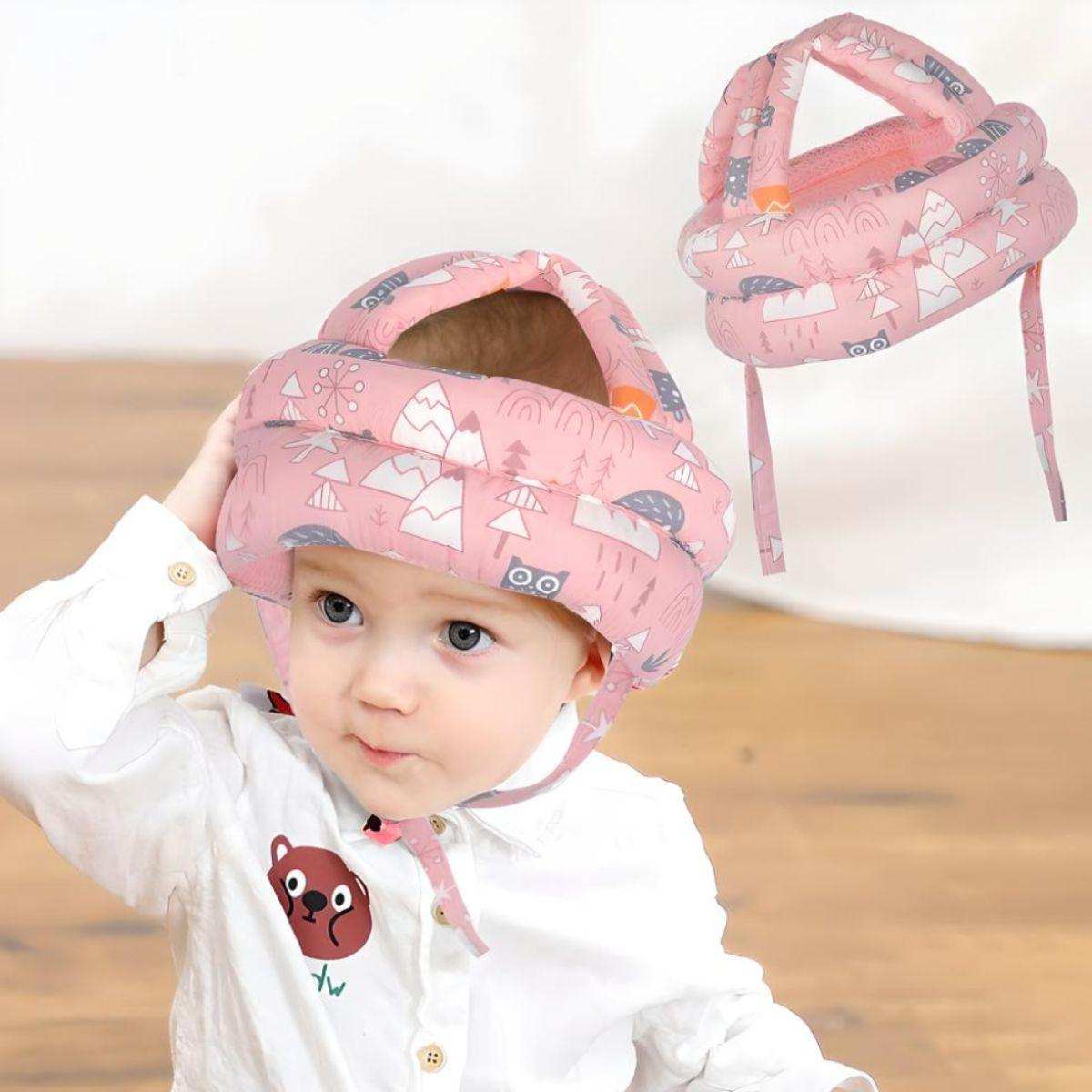 Baby wearing pink Feather & Fawn ProtectCap safety helmet with forest design, adjustable and breathable head cushion.