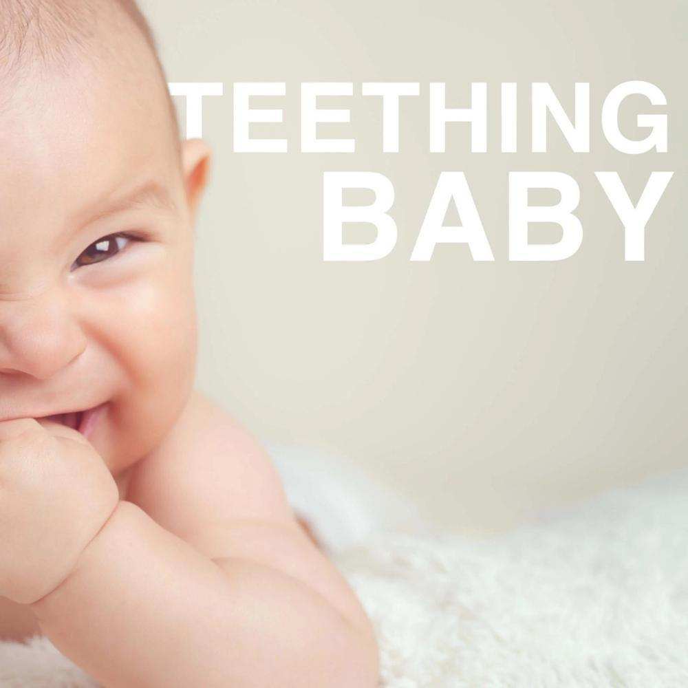 Happy baby chewing on teething ring to soothe gums