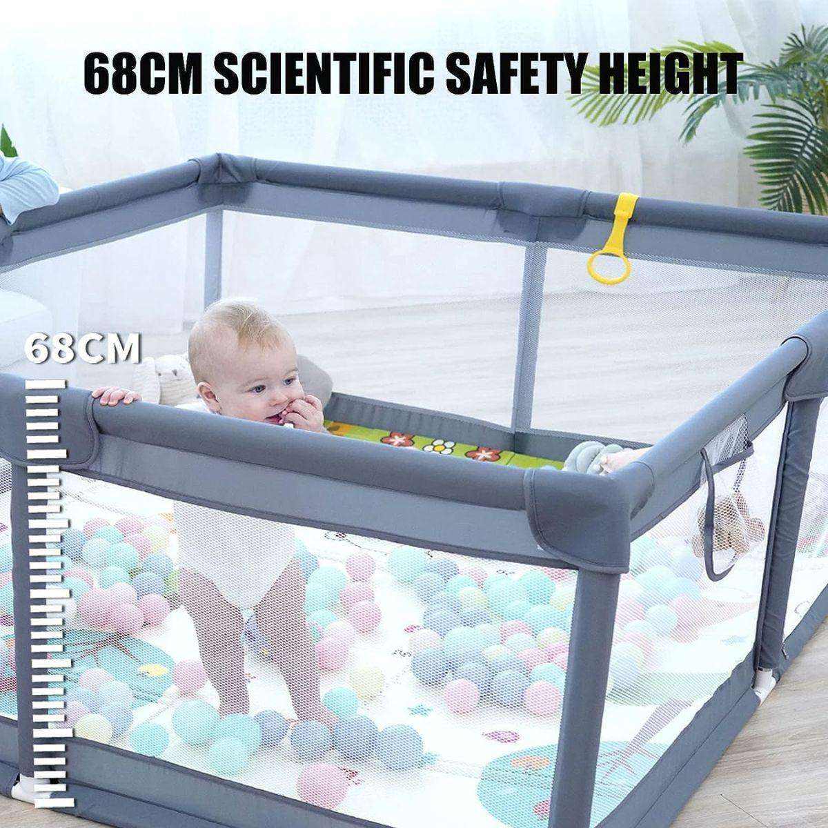 Baby standing in a grey baby playpen with mesh walls and colorful balls inside