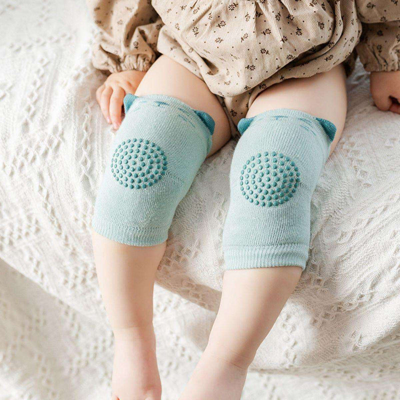 Baby wearing light blue Feather & Fawn CrawlGuard anti-slip knee pads sitting on a knitted blanket
